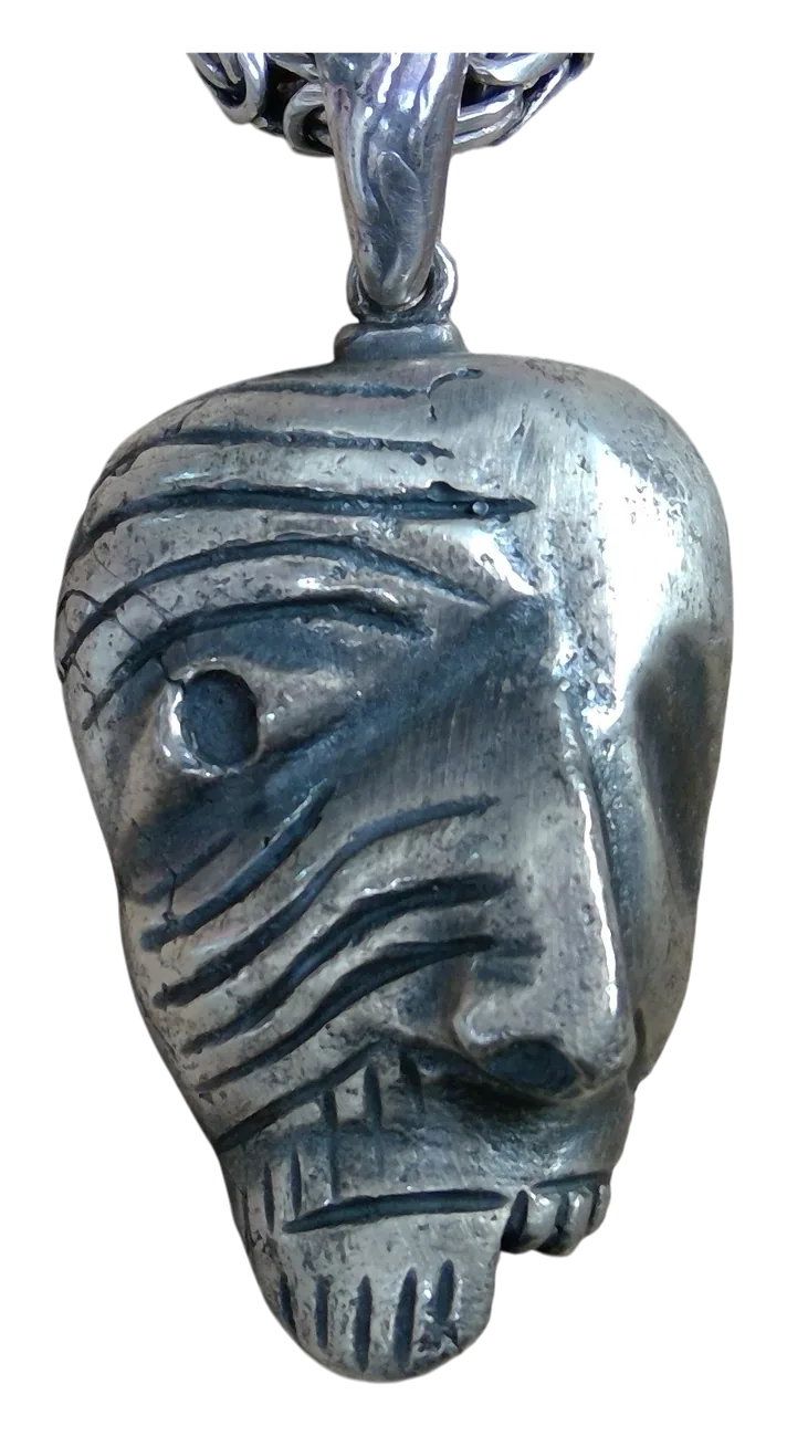 Dije de plata con forma de rostro de líneas talladas